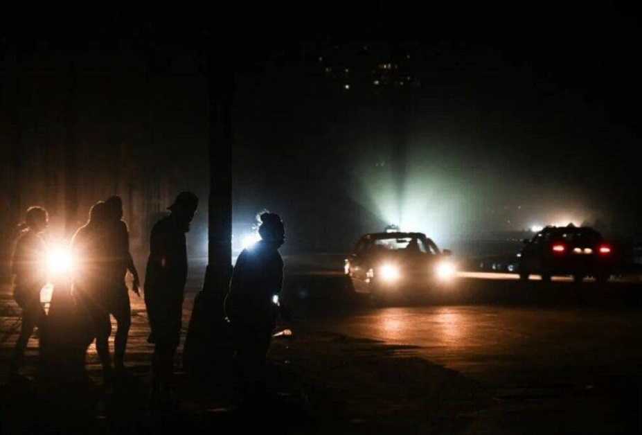 En la foto se ve un auto de policía en una calle cubana a oscuras