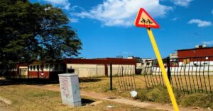 En la foto, una escuela y una señal de estudiantes delante