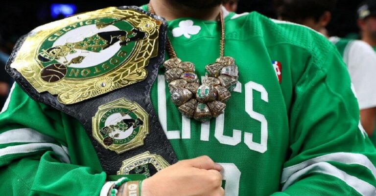 En la foto se ve una persona acariciando un cinturón de Boston Celtics con muchos anillos colgando del cuello