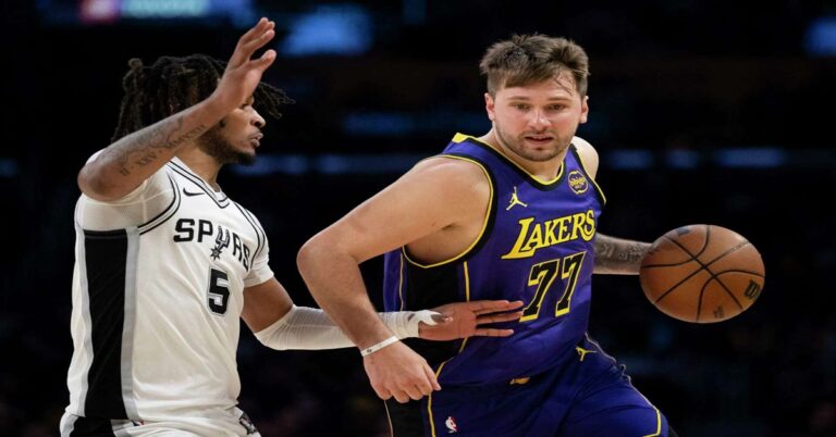 En la foto se ve a Luka Doncic, de los lakers, con un balón, marcado por un jugador de los Spurs