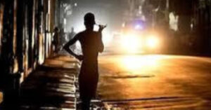 La imagen muestra una calle de La Habana apagada y un niño delante de las luces de un auto