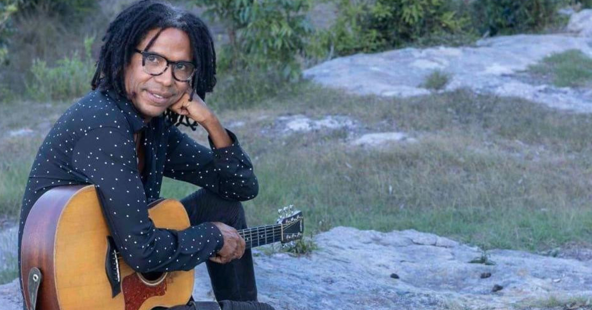 Foto de Raúl Torres sobre unas rocas con una guitarra