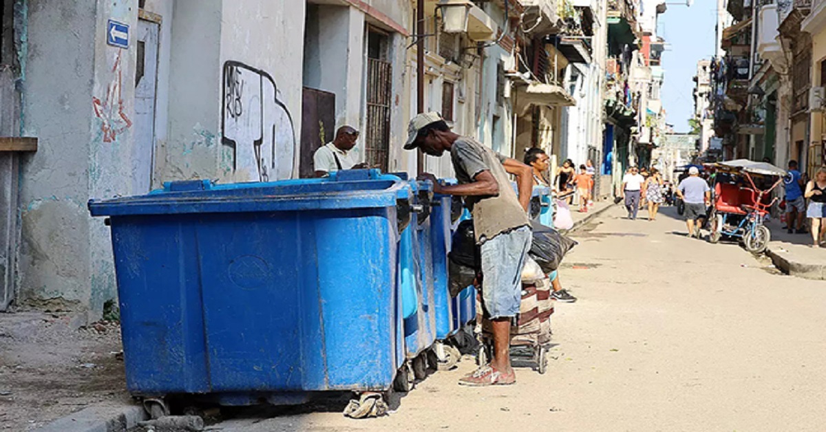 En la foto, una calle de Cuba, con gente buscando en la basura