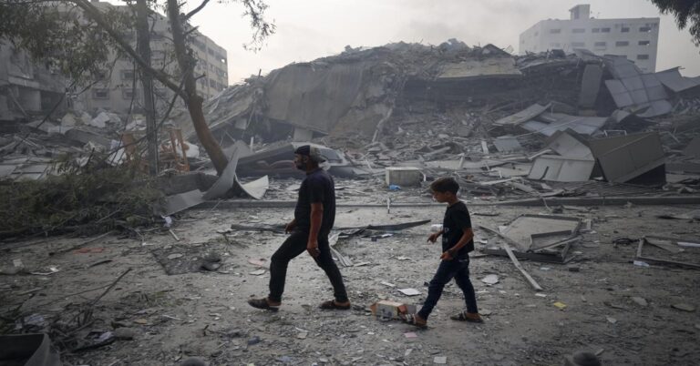 En la foto, un hombre y un niño caminan por una desolada y destruida Gaza