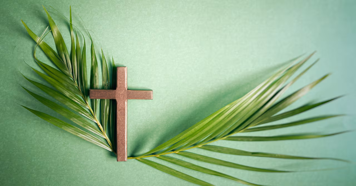 En la foto, una cruz acompañadas de una hojas de palmera