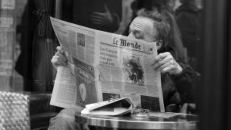 En la foto, un hombre lee Le Monde en un café de París