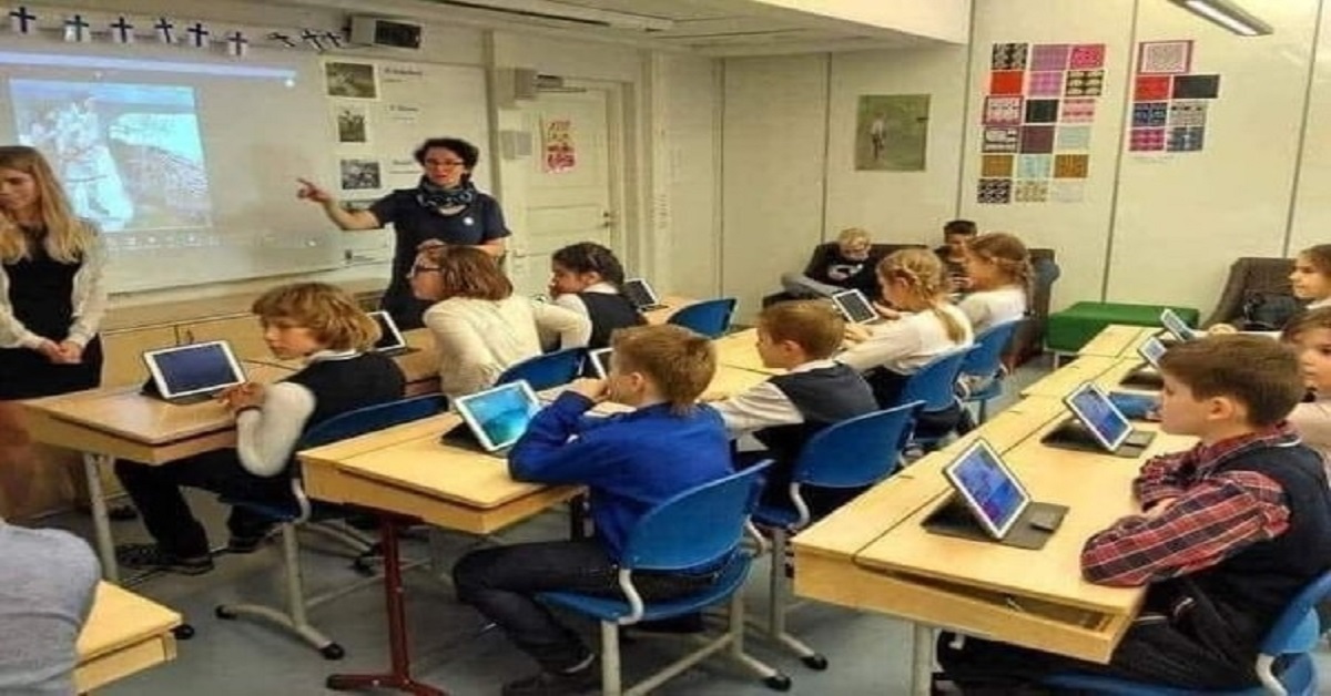 En la foto, una maestra con alumnos en un aula de Finlandia