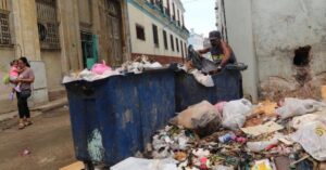 En la foto, un hombre husmea en la basura en una calle de Cuba