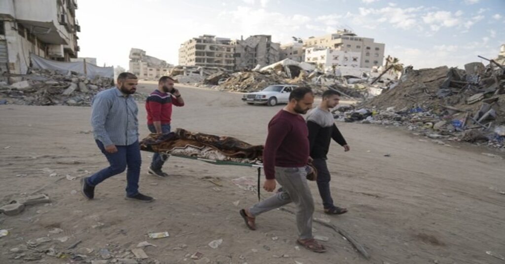 En la foto, cuatro hombres trasladan el cadáver de otra persona en Gaza