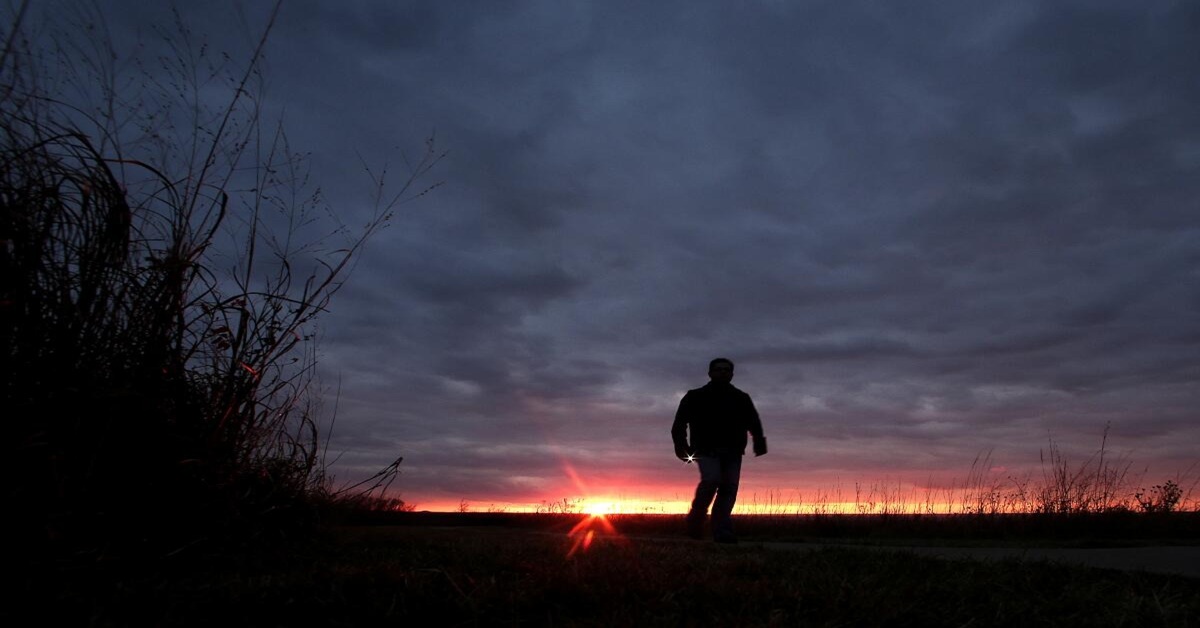 En la foto, un hombre camina hacia una luz, en un día turbio