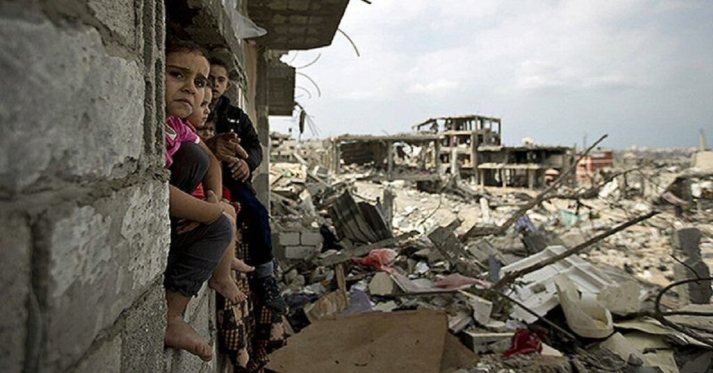 En la foto, niños al lado de un lugar destruido por las guerras