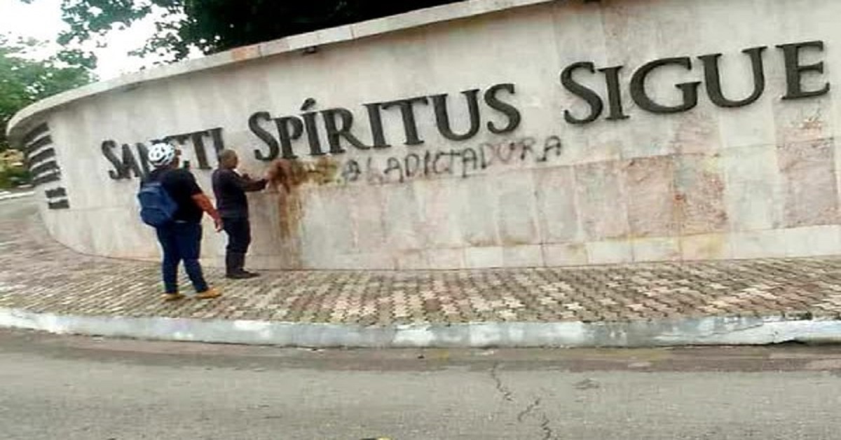 En la foto, plegados a la dictadura borran un letrero contra ella en una pared en Sancti Spíritus