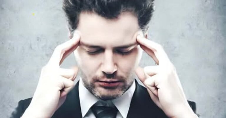En la foto, un hombre se toca las sienes con los dedos de las manos