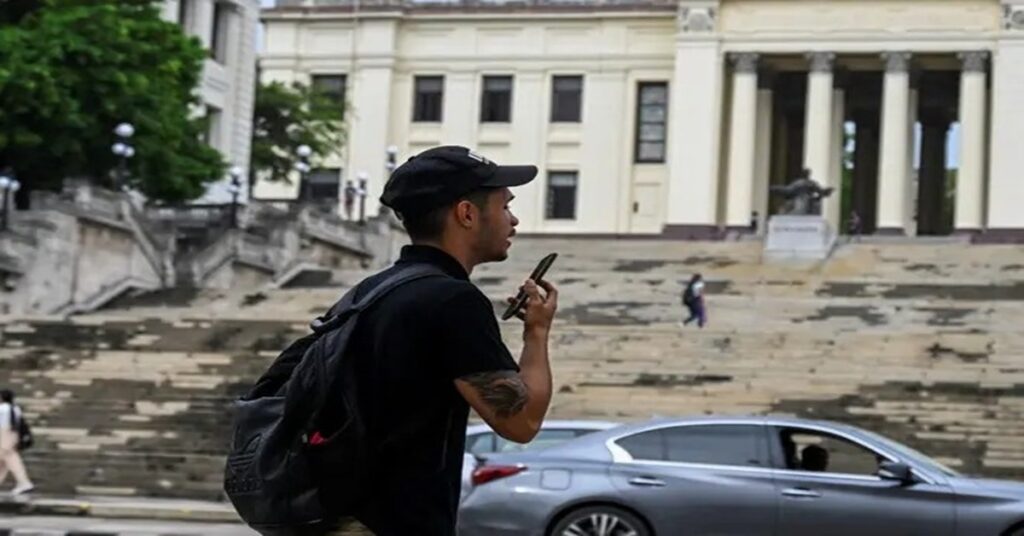 En la foto, un joven camina frente a la escalinata de la Universidad de La Habana