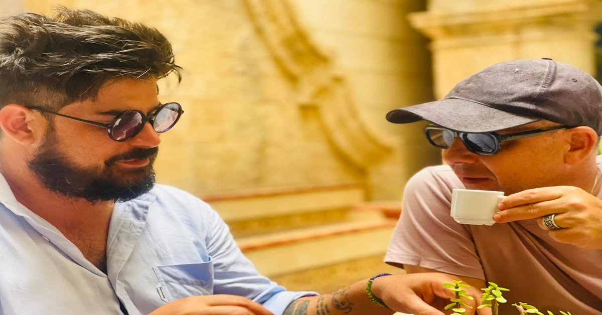 En la foto, el autor toma un café con un amigo