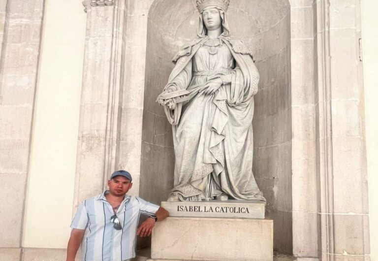 En la foto, el autor posa ante una estatua de isabel, La Católica