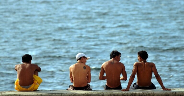 En la foto, unos jóvenes cubanos sentados frente al mar