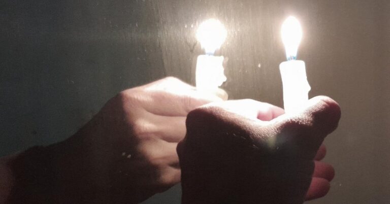 En la foto, dos personas sostienen dos velas