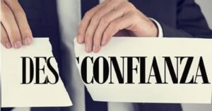 En la foto, unas manos rompen un letrero que dice 'desconfianza'