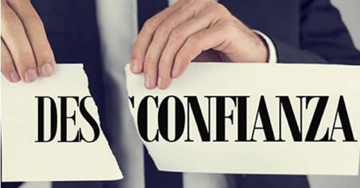 En la foto, unas manos rompen un letrero que dice 'desconfianza'