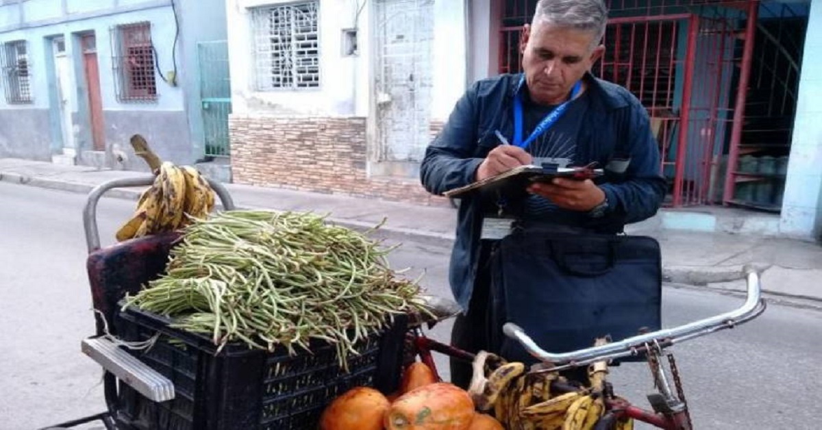 En la foto, un inspector multa a un vendedor callejero en una calle de Cuba