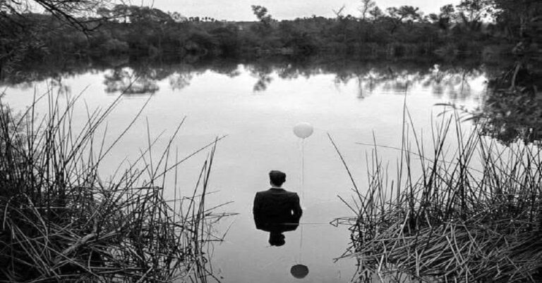 En la foto, un hombre metido en el agua con ropa incluso