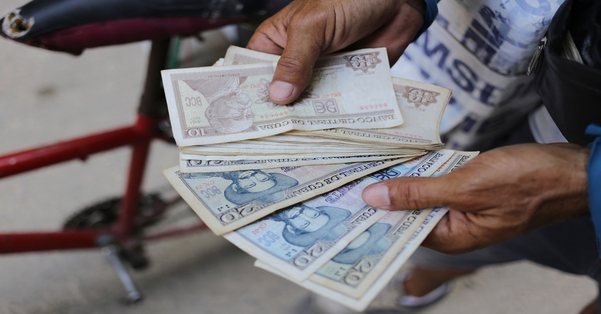En la foto, un hoombre sostiene unos billetes cubanos