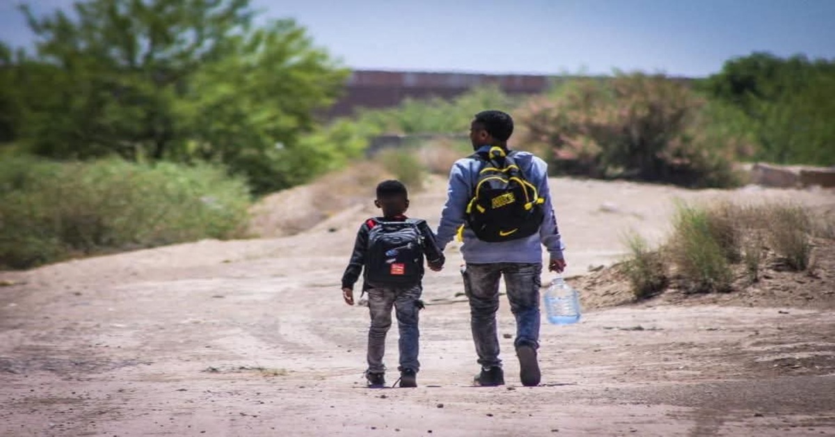 En la foto,un hombre camina hacia un destino incierto con un niño de la mano