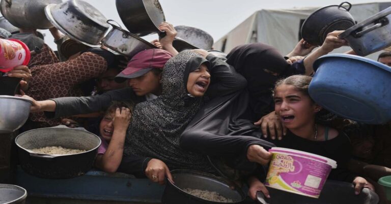 En la foto, personas gritan cerca de un área de distribución de alimentos
