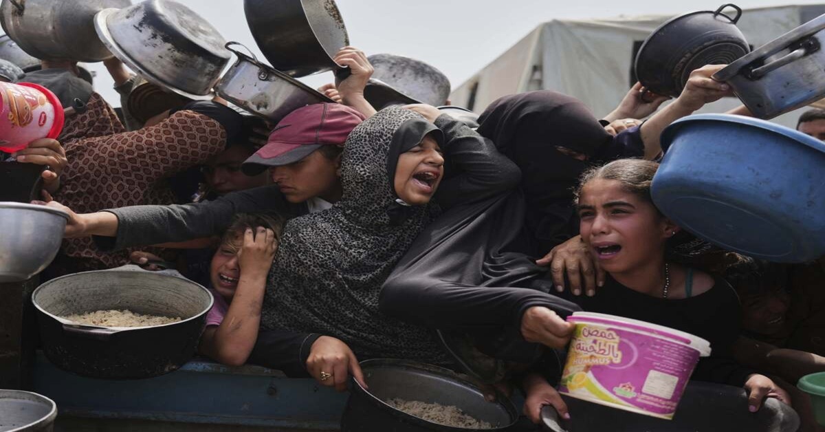 En la foto, personas gritan cerca de un área de distribución de alimentos