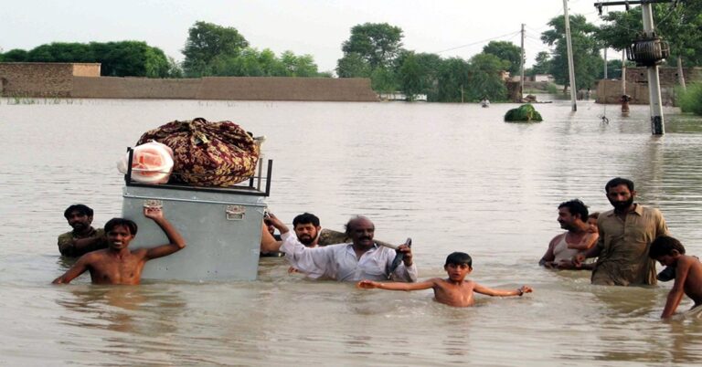 En la foto, personas huyen de las inundaciones en Pakistán