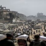 En la foto, habitantes de Gaza cargan sacos de harina cerca de un lugar de reparto