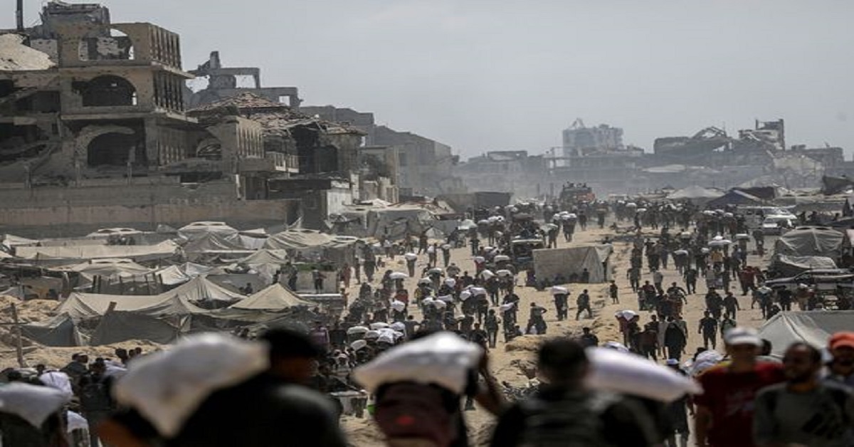 En la foto, habitantes de Gaza cargan sacos de harina cerca de un lugar de reparto