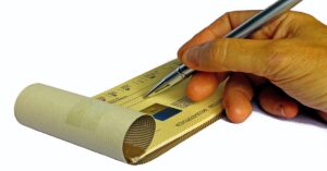 En la foto, un hombre firma un cheque