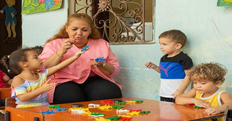 En la foto, una maestra enseña a unos niños