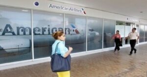 En la foto, una mujer camina cerca de una oficina de American Airlines