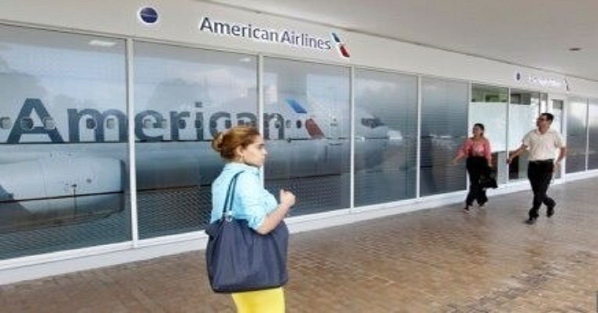 En la foto, una mujer camina cerca de una oficina de American Airlines