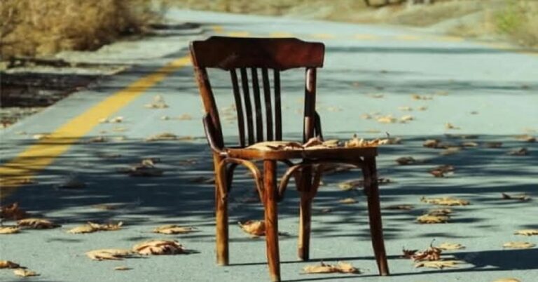 En la foto, una silla abandonada en una carretera abandonada