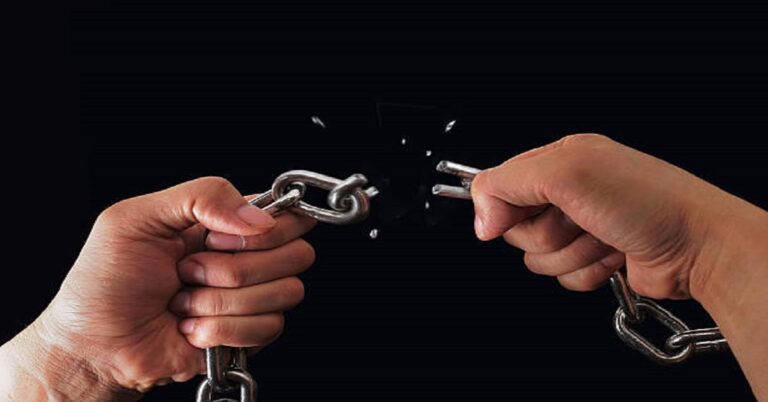 En la foto, dos manos sostienen una cadena rota