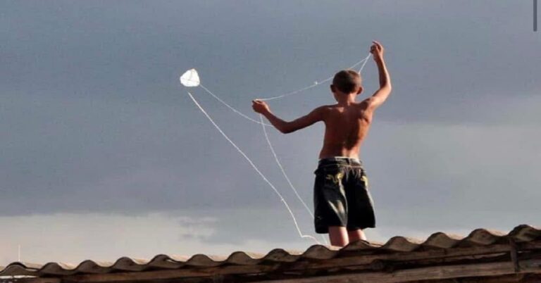 En la foto, un niño empina pappalotes sobre un techo