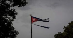 En la foto, una bandera cubana rota, en un día oscuro, tormentoso
