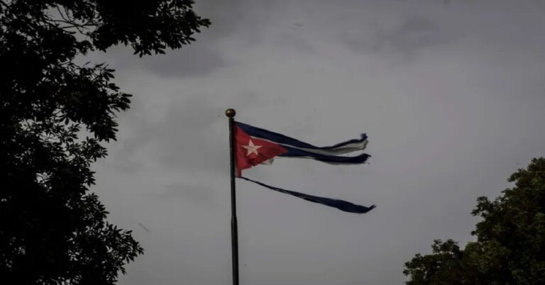 En la foto, una bandera cubana rota, en un día oscuro, tormentoso