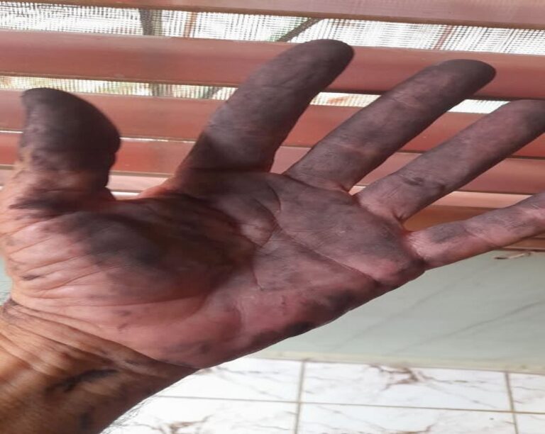 En la foto, una mano tiznada con carbón