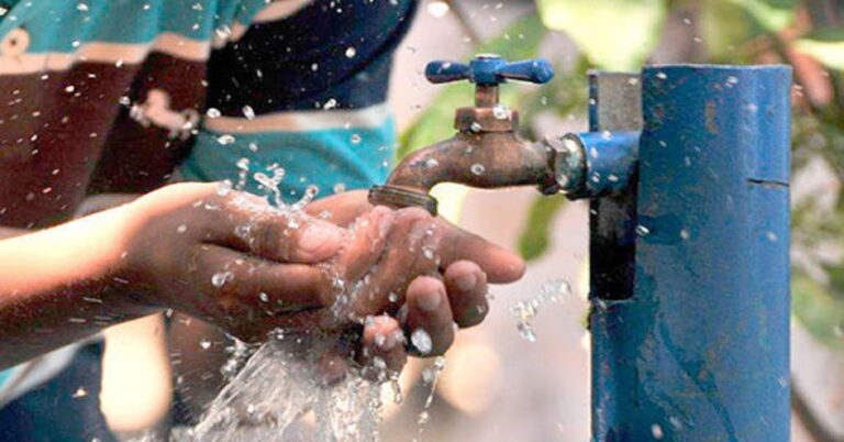 En la foto, un hombre toma agua de una llave