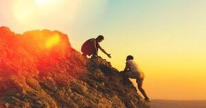 En la foto, una persona ayuda a otra a subir algún promontorio