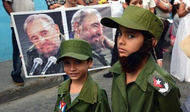 En la foto, niños vestidos de militares delante de fotos de Fidel Castro