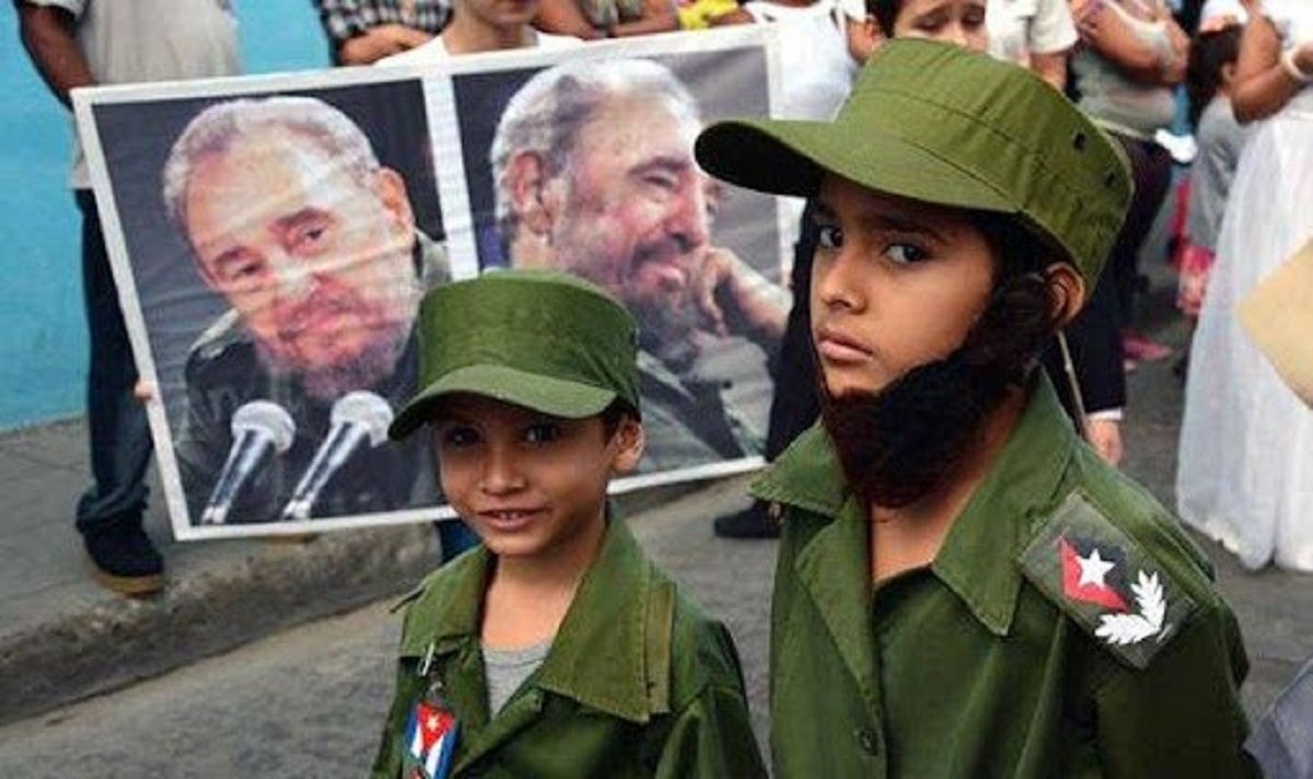 En la foto, niños vestidos de militares delante de fotos de Fidel Castro