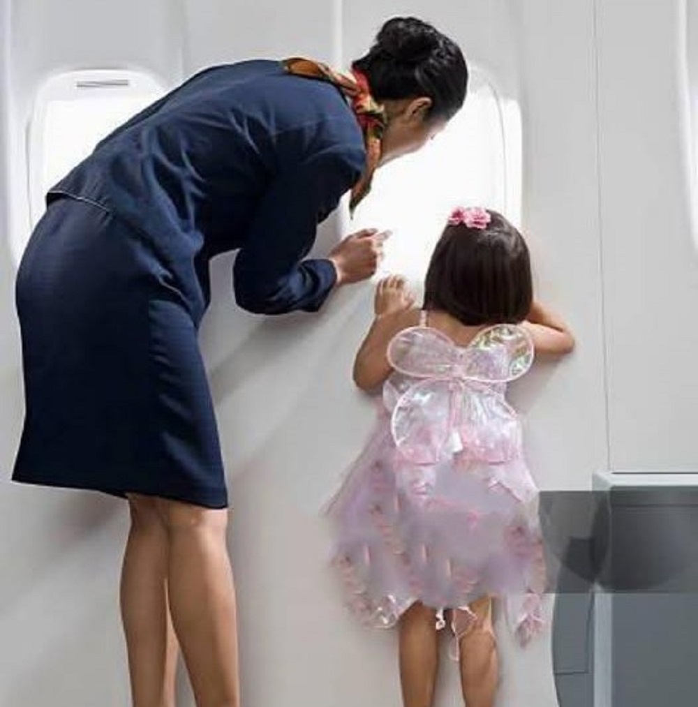 En la foto, una niña mira por la ventanilla de un avión