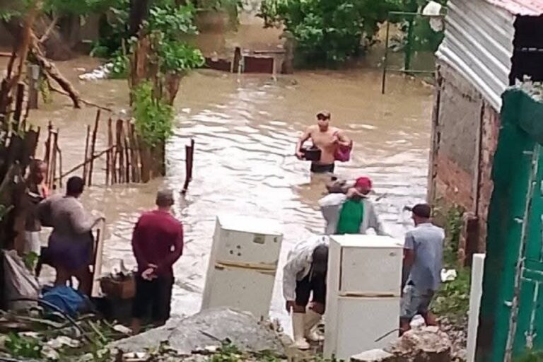 En la foto, personas intentan rescatar de las aguas útiles del hogar