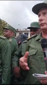 En la foto, el tirano Díaz-Canel habla y un escolta mantiene su mano en el pomo de una pistola